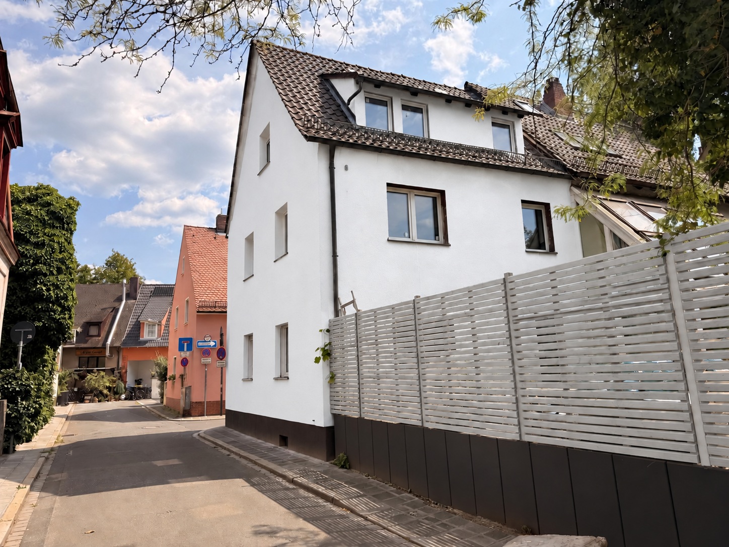 Gartenseite mit weißer Fassade und grauem Gartenzaun